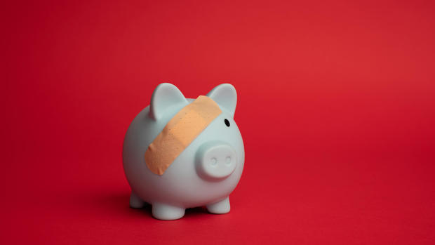 Broken piggy bank with beige adhesive on red background. 