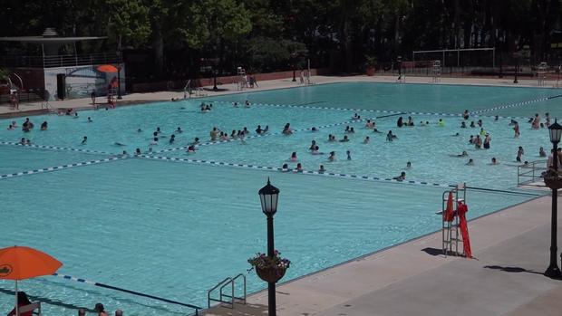 People swim in the middle section of Astoria Pool. Two large sections on either end of the pool remain empty. 