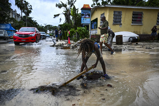People clear debris from a street flooded by Hurricane Beryl 