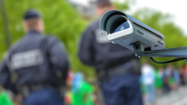 security CCTV camera or surveillance system with police officers on blurry background 