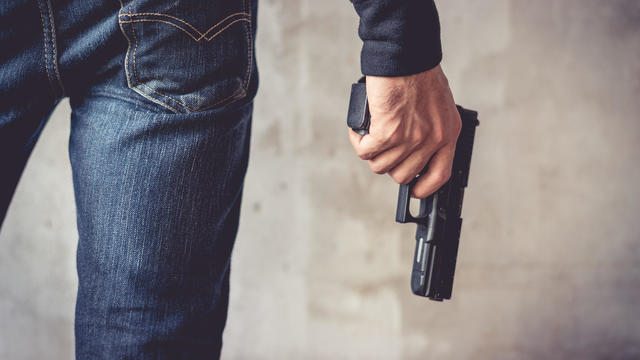 Close up of man holding hand gun. Man wearing blue jeans. Terrorist and Robber concept. Police and Soldier concept. Weapon theme 