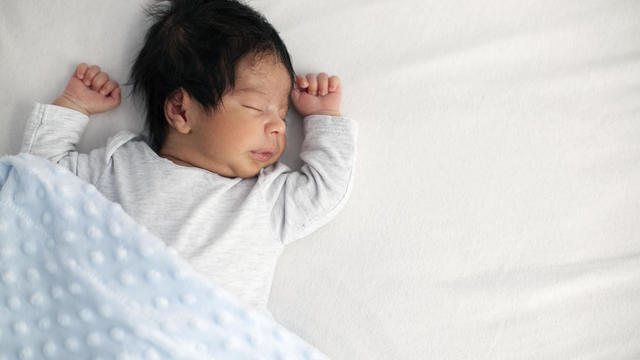 African American newborn baby sleeping on a white mattress 