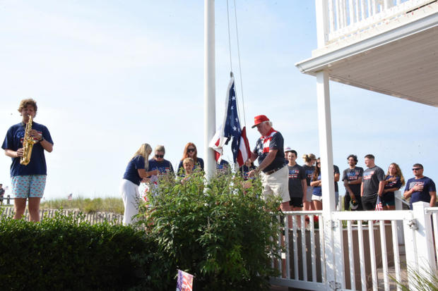 People look on as someone raises a flag in Ocean City 