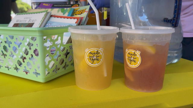 Two fresh lemonades sit on a table next to a basket of children's books 