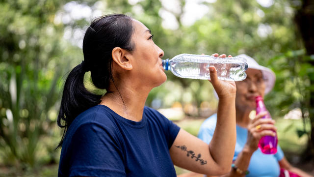Mature woman drinking water on the public park 
