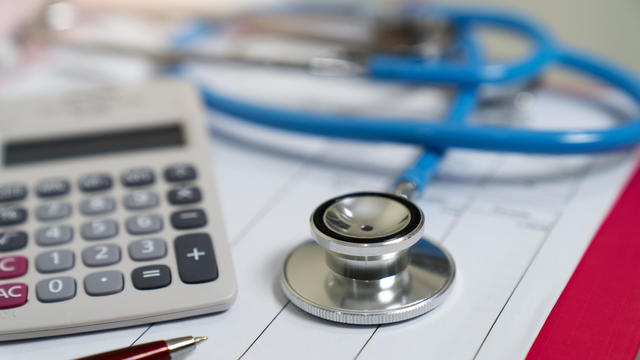 Cost of health care concept, stethoscope and calculator on document 