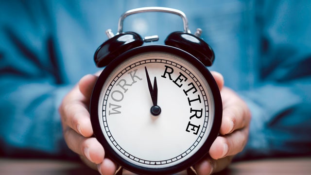 Businessman holding black alarm clock with clockwise countdown from work to retirement.