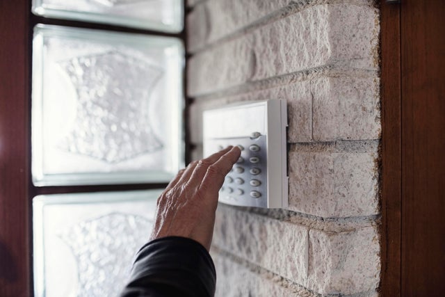 Cropped image of senior man using electronic lock on wall outside house 