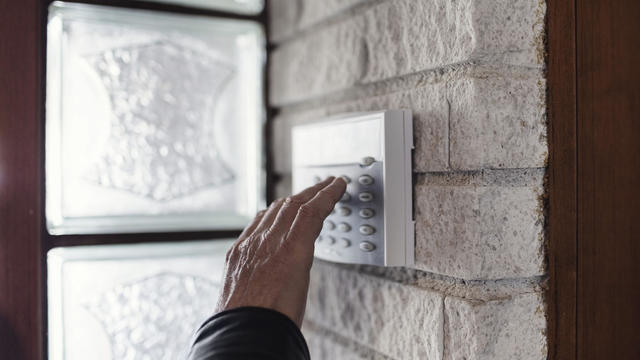 Cropped image of senior man using electronic lock on wall outside house 