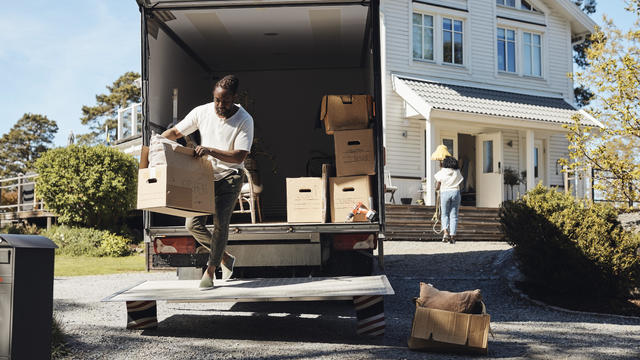 Full length of man unloading cardboard box from van 