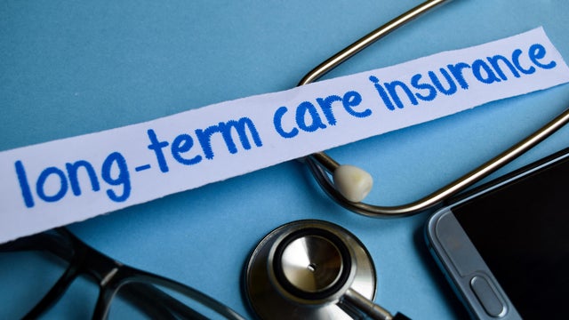 Long-term care insurance inscription with the view of stethoscope, eyeglasses and smartphone on the blue background 