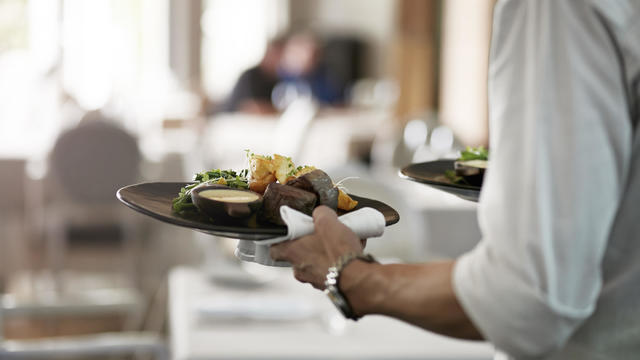 Close-up of waiter walkiing with dishes 