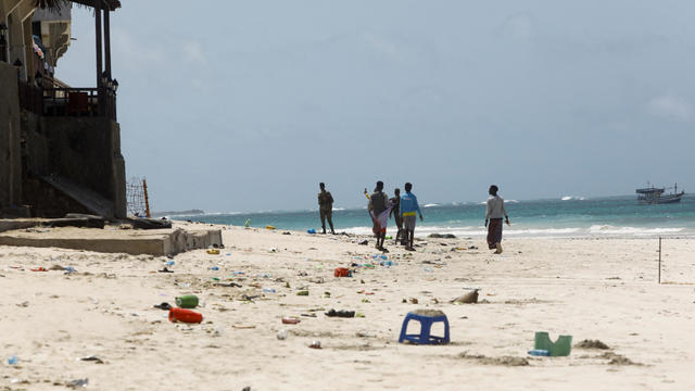 People walk at the scene of an explosion that occurred while revellers were swimming at the Lido beach in Mogadishu 