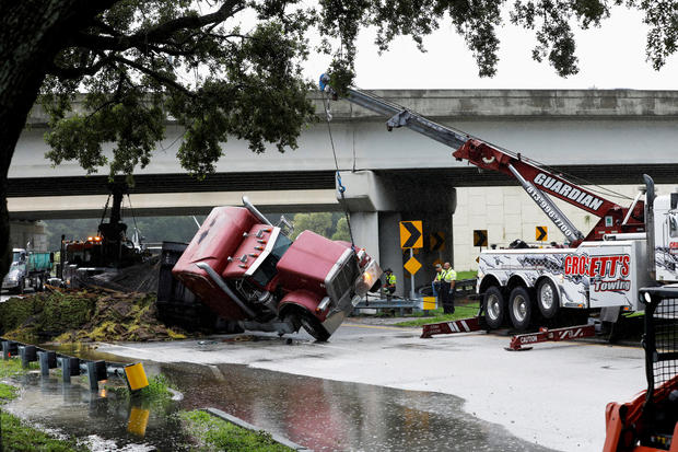 Tow trucks lift a transfer truck that overturned on Independence Parkway in Tampa as Hurricane Debby moves north of central Florida 