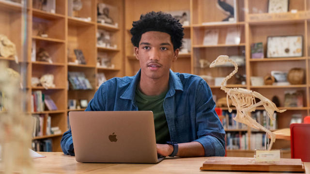 Woman holding camera using MacBook 