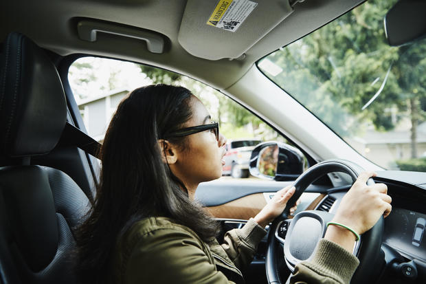 Young woman sitting in drivers seat of car waiting for driving lesson 