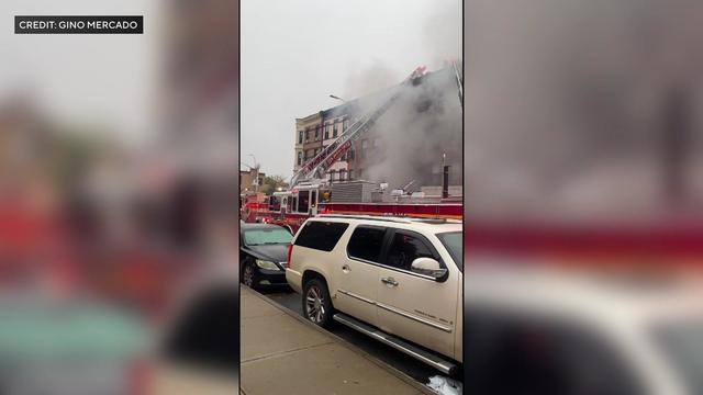 A fire truck extends its ladder to an apartment building as smoke pours out. 