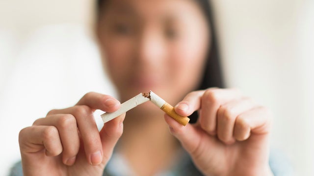 Mixed race teenage girl breaking cigarette in half