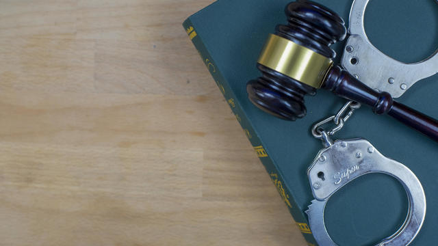 Gavel And Handcuffs On The Law Book Over The Wooden Table Background 