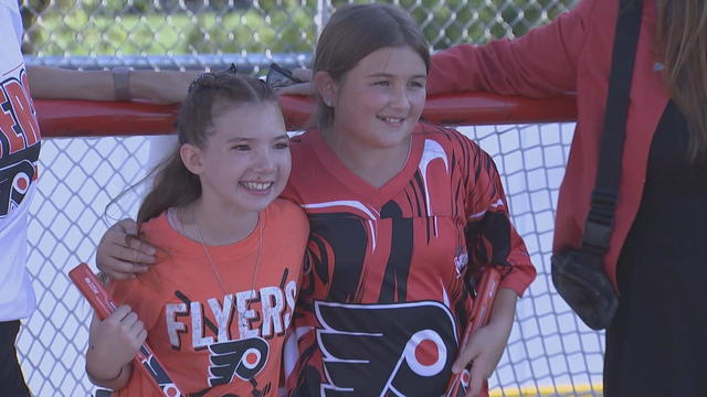 Natalie and Lilly, wearing Flyers shirts, post for a photo in front of one of the nets at the new rink 