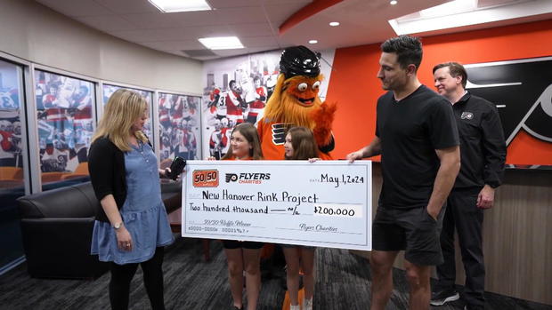 The girls post for a photo with Gritty and a big check from Flyers Charities 