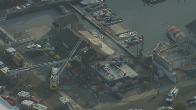 Overhead photo of fire crews working on a building with smoke coming out 