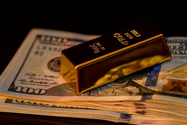 Gold bullion on dollar banknotes with dark background