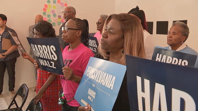 People hold signs for Kamala Harris' campaign during an event at a campaign office 