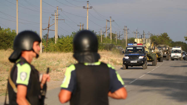 Law enforcement officers drive along a road following the seizure of hostages by a group of inmates in a penal colony in Surovikino 