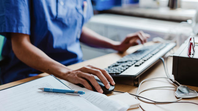 Midsection of nurse using computer at desk in hospital 