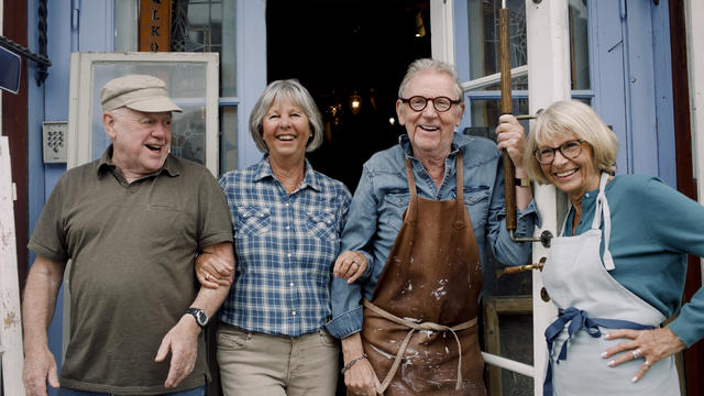 Portrait of smiling senior male and female coworkers standing at store entrance 