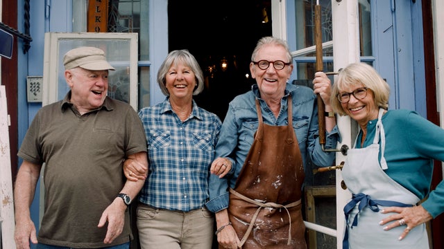 Portrait of smiling senior male and female coworkers standing at store entrance