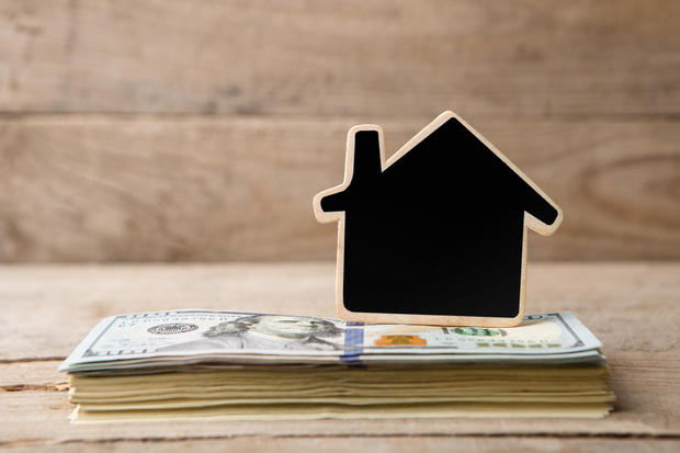 Dollar bills, blank blackboard in the shape of a house 