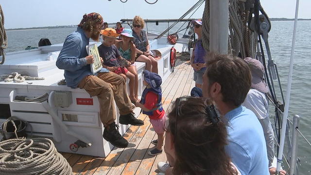 Kids gather around as someone explains the history of the ship 