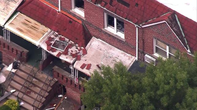 An overhead view of several damaged homes in Brooklyn. Windows are blown out and some bricks lay on the porch roof. 