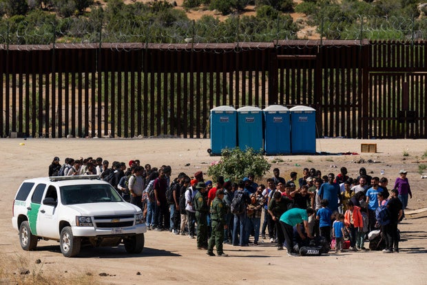 Migrants wait to be processed by U.S. Border Patrol agents after crossing into the U.S. from Mexico on June 14, 2024, in Jacumba Hot Springs, California.