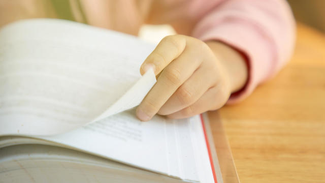 USA, New Jersey, Jersey City, Close up of girl's (8-9) hand turning pages 