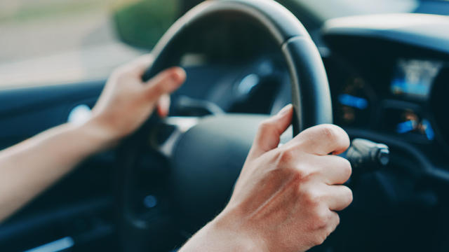 Male hands holding steering wheel in a car 