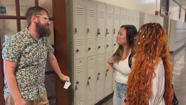 A teacher speaks to two high school students 