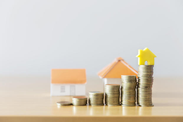 golden coins with house icon on wooden table with bokeh green background for growth up saving to buy house, mortgage or home loan concept 