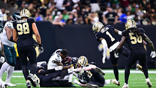 DeVonta Smith #6 of the Philadelphia Eagles loses his helmet after being tackled by Paulson Adebo #29 and Kendal Vickers #91 of the New Orleans Saints at Caesars Superdome on September 22, 2024 in New Orleans, Louisiana. 