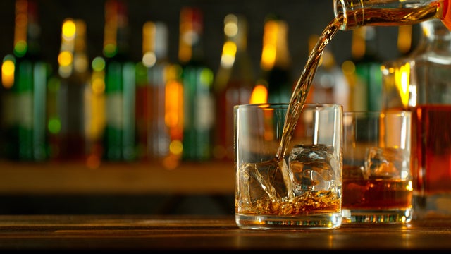 Close-up of pouring whiskey or rum on the bar
