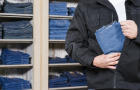 Shoplifter stealing denim jeans in his jacket 