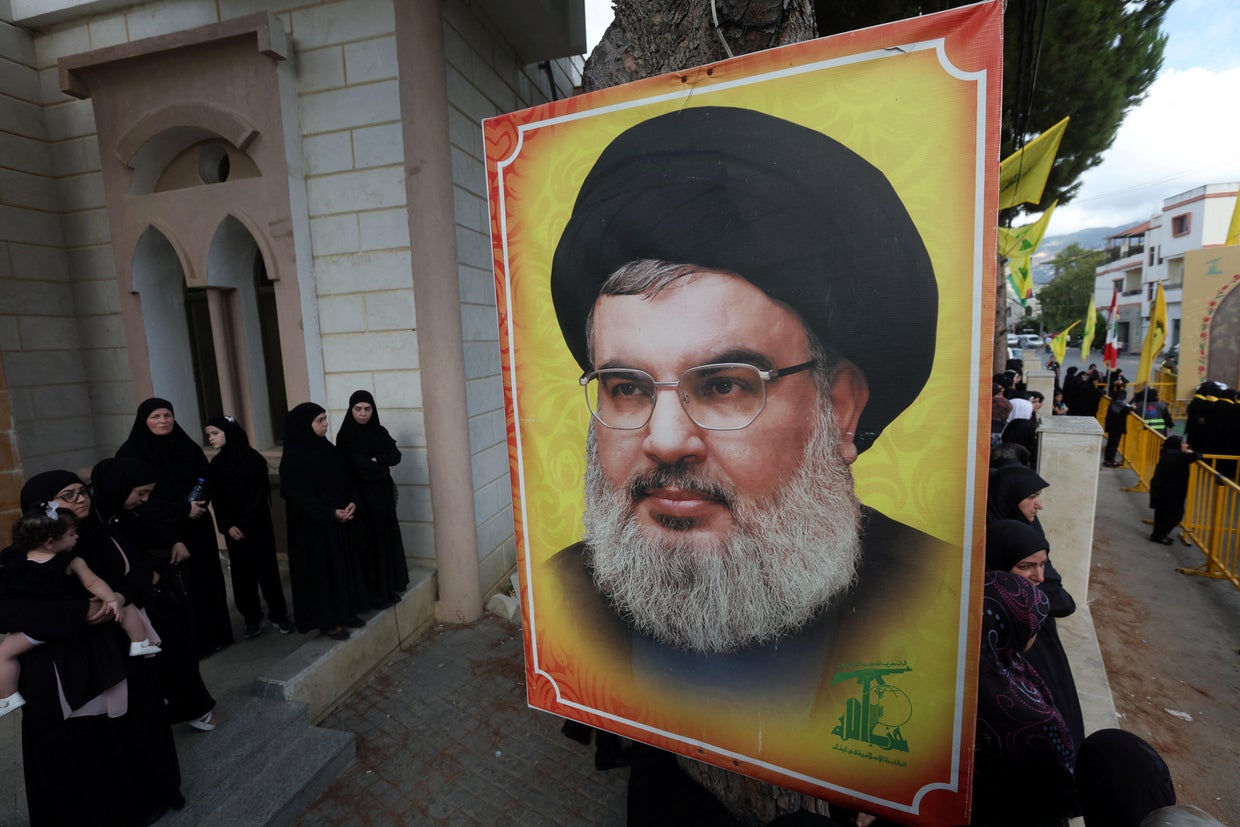 People stand near a picture of Hezbollah leader Sayyed Hassan Nasrallah 