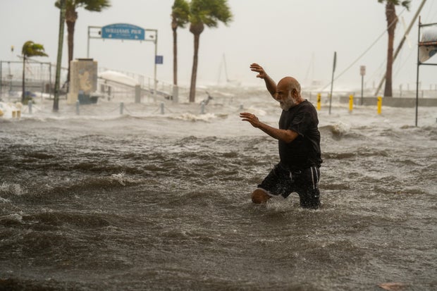 A man crosses a storm surge flooded area on the coast of Gulfport, Florida, as Hurricane Helene passed through the Gulf of Mexico to the west on Sept. 26, 2024.