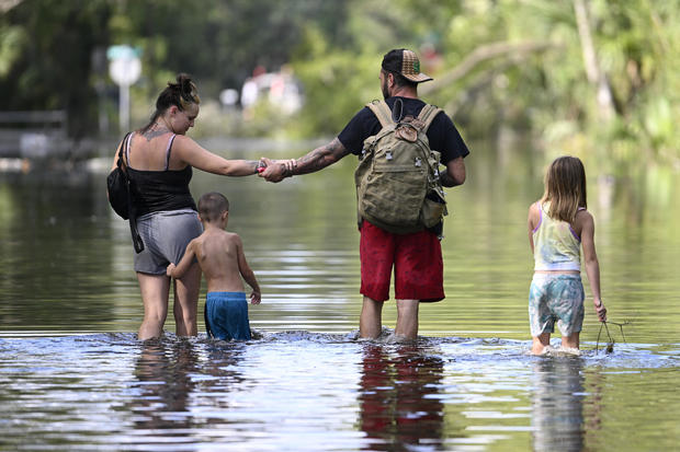 Dustin Holmes, second from right, holds hands with his girlfriend, Hailey Morgan, while returning to their flooded home with her children Aria Skye Hall, 7, right, and Kyle Ross, 4, in the aftermath of Hurricane Helene, Sept. 27, 2024, in Crystal River, Florida. 