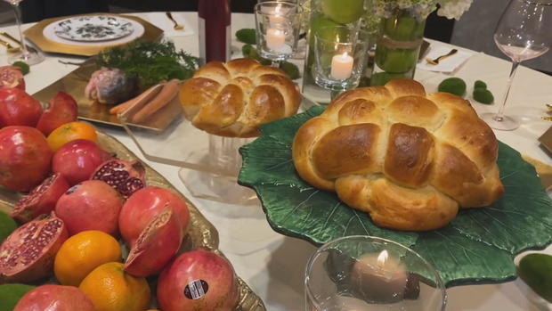 A table set with platters of fruits and challah 