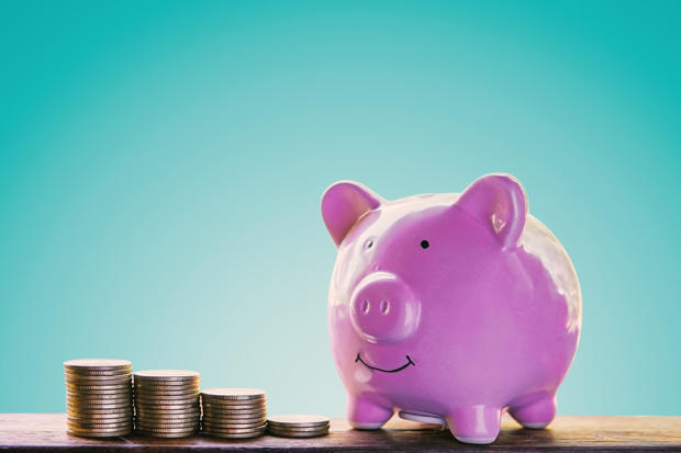 Piggy bank and coins on wood plank with blue background, saving and growing concept. 