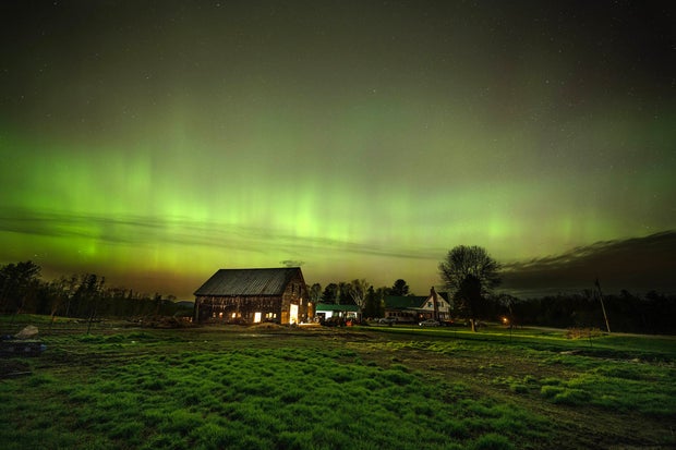 The northern lights fill the sky with green over the barn and pastures at Greaney's Turkey Farm in Mercer, Maine, on May 11, 2024.