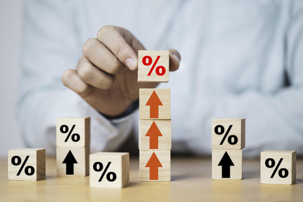 Businessman putting percentage sign which print screen on wooden cube block to up arrow for business profit and economic growth concept. 